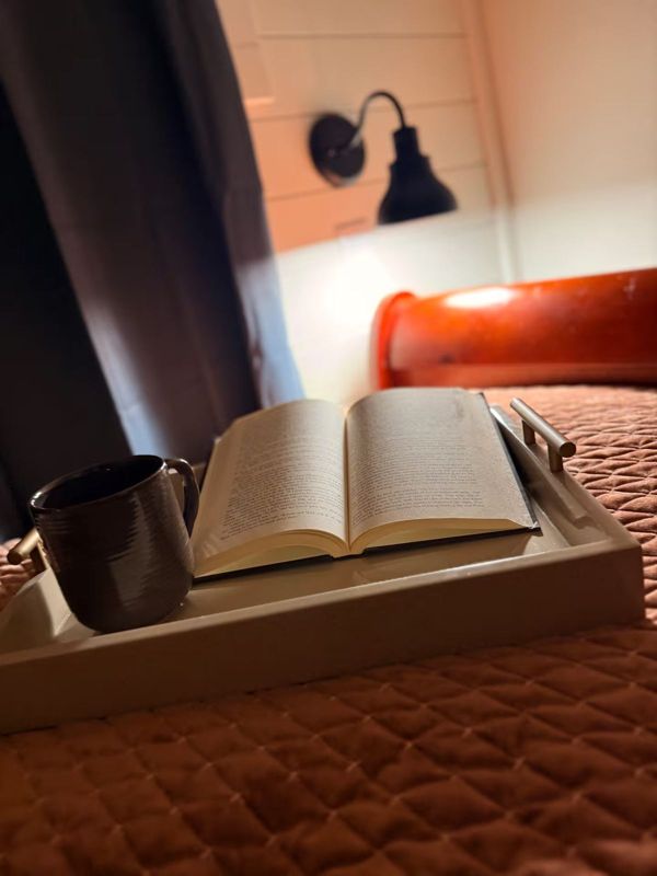 Coffee and a book on a tray on the queen bed at The Waxahachie Tiny Home